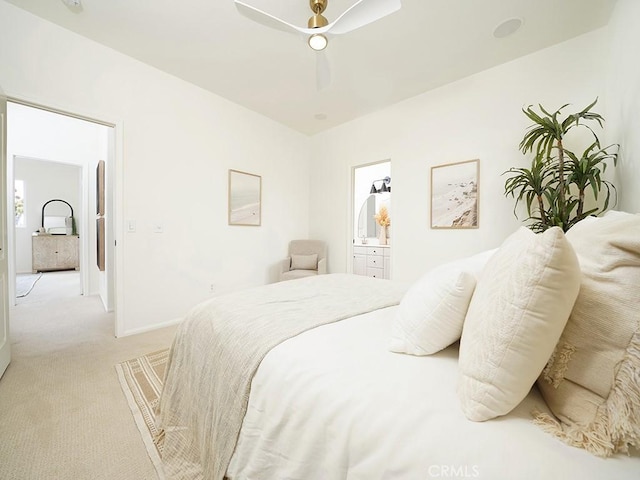 bedroom featuring baseboards, light carpet, ensuite bath, and ceiling fan