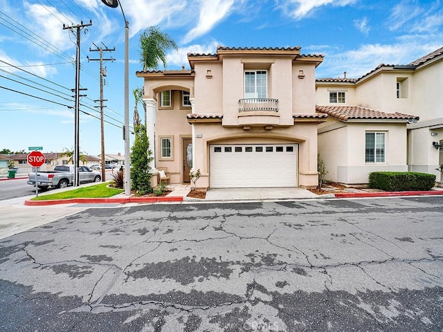 view of front facade with stucco siding, driveway, a tile roof, and a garage