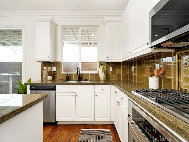 kitchen with dark wood-style flooring, a sink, decorative backsplash, stainless steel appliances, and white cabinets