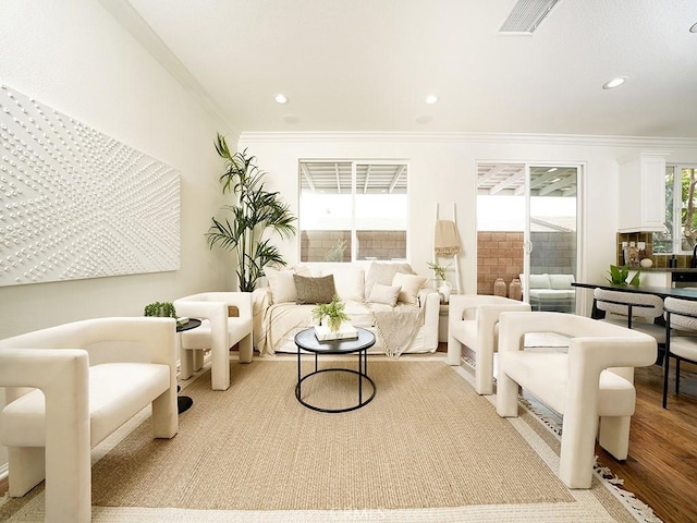 living area featuring crown molding, recessed lighting, wood finished floors, and visible vents