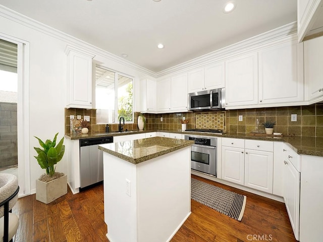 kitchen with a sink, tasteful backsplash, dark wood-style floors, appliances with stainless steel finishes, and white cabinets