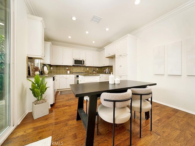 kitchen with dark wood finished floors, decorative backsplash, stainless steel appliances, and ornamental molding