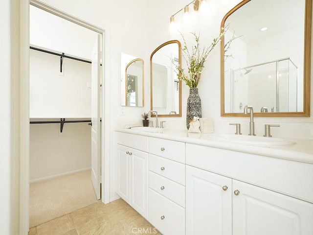 bathroom featuring double vanity, a walk in closet, and a sink