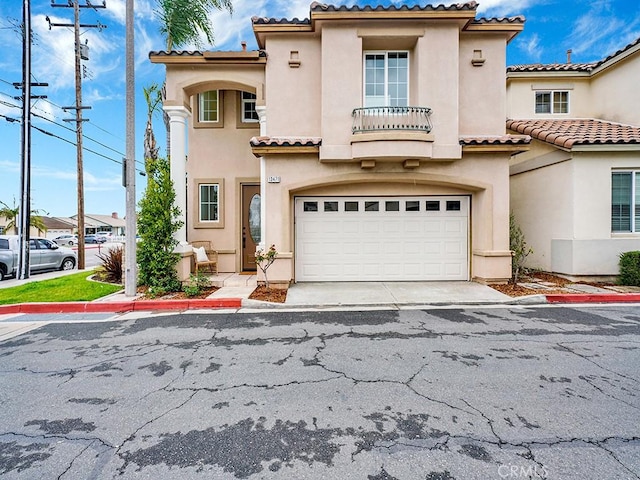 mediterranean / spanish house with stucco siding, a tile roof, and a garage