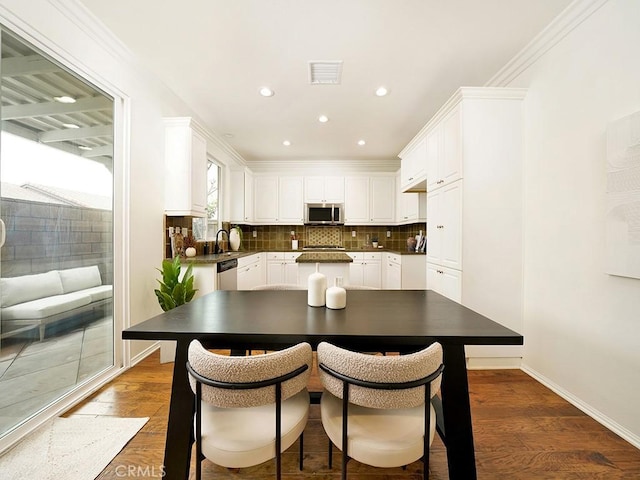 kitchen with visible vents, stainless steel appliances, dark wood-type flooring, white cabinets, and backsplash