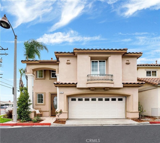 mediterranean / spanish home with a tiled roof, a garage, driveway, and stucco siding