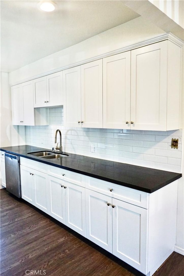 kitchen with dishwasher, dark countertops, white cabinetry, and a sink