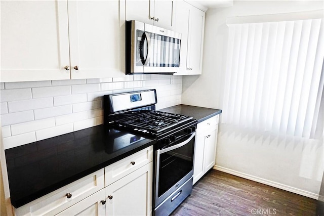 kitchen featuring backsplash, dark countertops, appliances with stainless steel finishes, and white cabinets