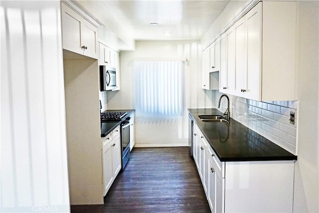 kitchen with a sink, dark countertops, dark wood finished floors, appliances with stainless steel finishes, and decorative backsplash