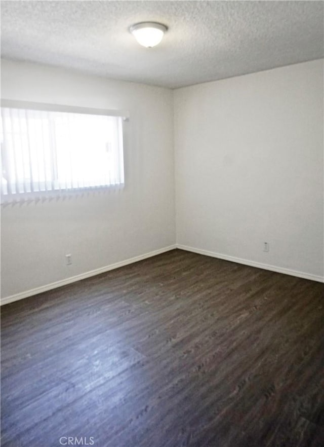 empty room with baseboards, dark wood-style flooring, and a textured ceiling