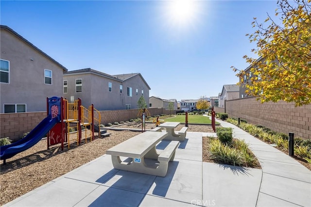 view of patio featuring fence, playground community, and a residential view