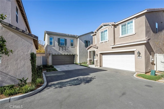 traditional-style home with stucco siding, an attached garage, and driveway