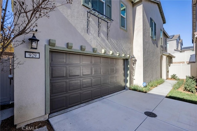 garage featuring driveway and fence