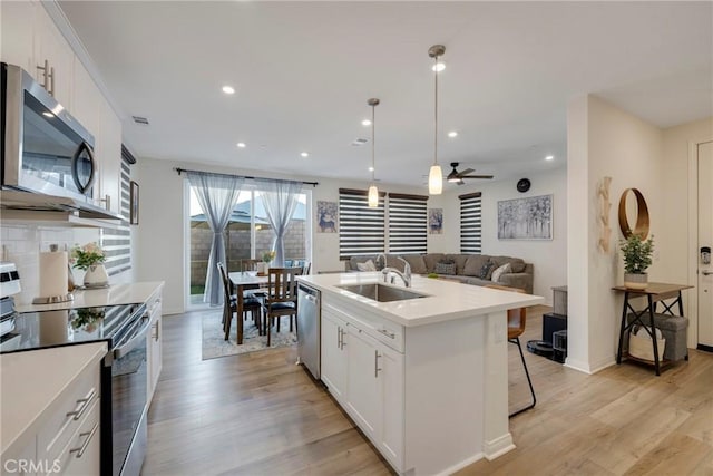 kitchen featuring tasteful backsplash, appliances with stainless steel finishes, light wood-type flooring, and a sink