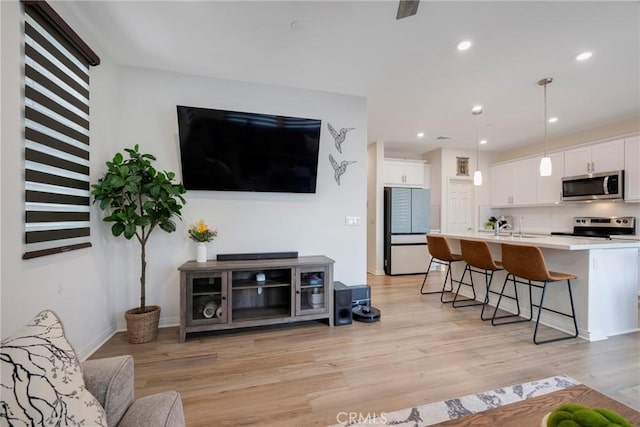 living room featuring recessed lighting, baseboards, and light wood finished floors