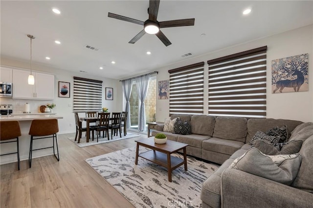 living room featuring a ceiling fan, light wood-style flooring, recessed lighting, and visible vents