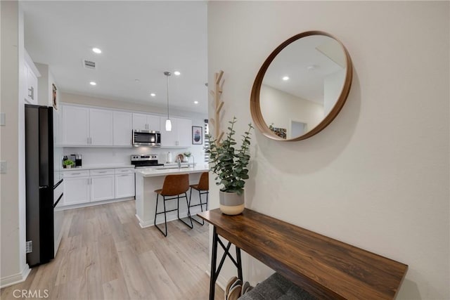 kitchen with visible vents, light countertops, light wood-style floors, white cabinets, and stainless steel appliances