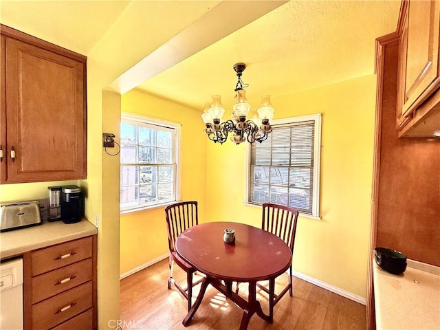 dining space featuring baseboards, an inviting chandelier, and light wood finished floors