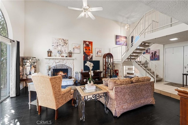 living room with stairs, high vaulted ceiling, dark wood-style floors, and a fireplace