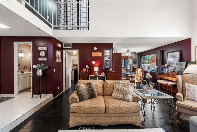 living area with visible vents, wood finished floors, a ceiling fan, and a towering ceiling