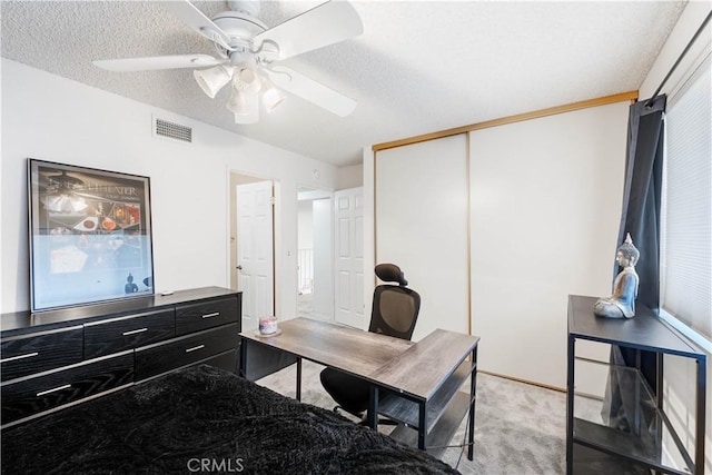 home office with visible vents, light colored carpet, a textured ceiling, and a ceiling fan