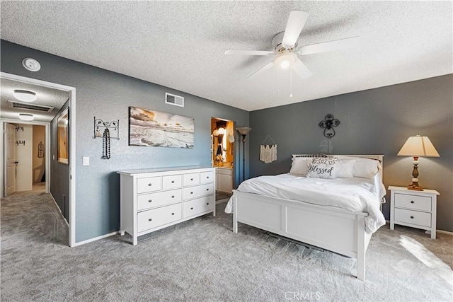 carpeted bedroom featuring a ceiling fan, a textured wall, visible vents, and a textured ceiling