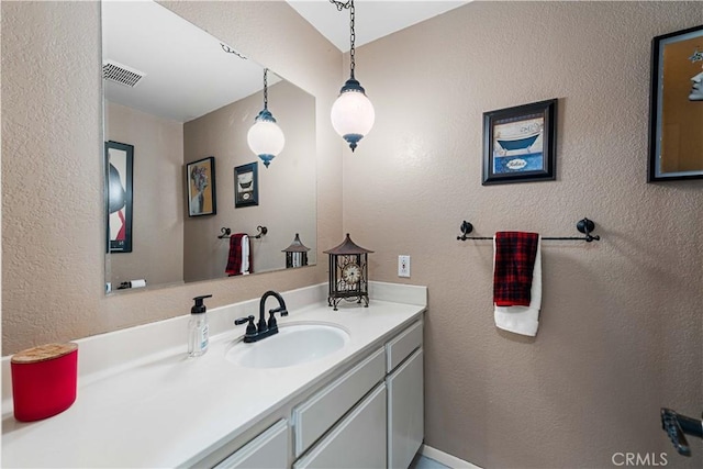 bathroom with visible vents, vanity, and a textured wall