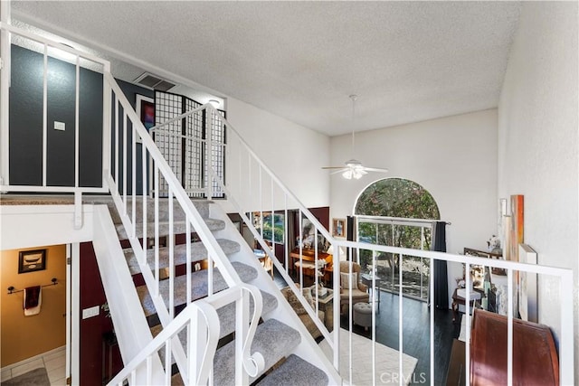 stairs featuring visible vents, a textured ceiling, and ceiling fan