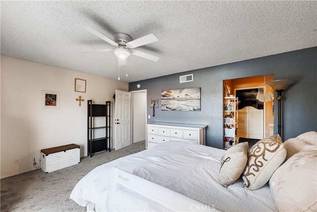 bedroom with visible vents, a textured ceiling, carpet, and a ceiling fan