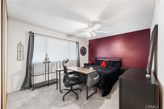 bedroom with light colored carpet, a textured ceiling, an accent wall, and a ceiling fan