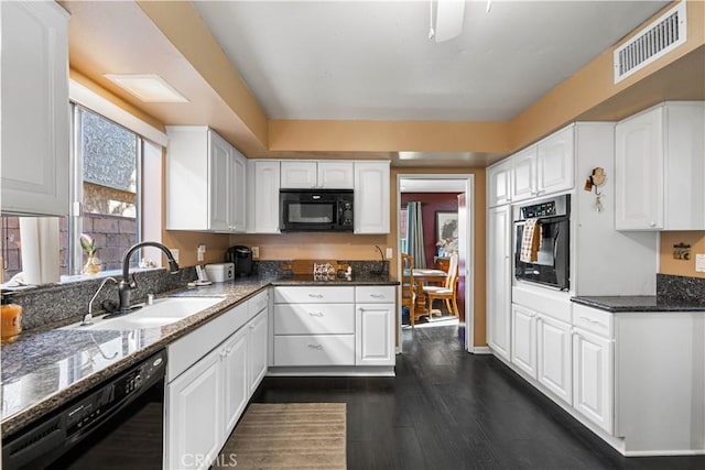 kitchen with dark stone countertops, visible vents, a sink, black appliances, and white cabinets