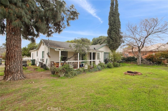 view of property exterior featuring a fire pit, stucco siding, cooling unit, a yard, and a sunroom