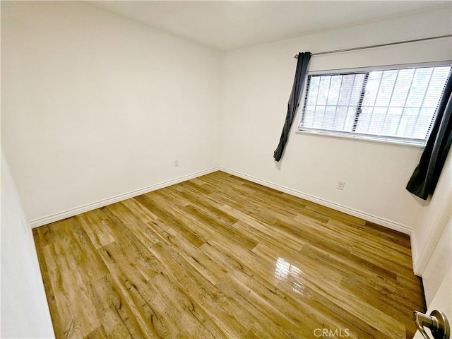 empty room featuring wood finished floors and baseboards