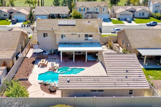 rear view of property with a patio, a fenced backyard, a pool with connected hot tub, a tile roof, and a residential view