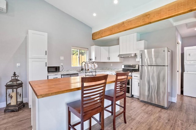 kitchen featuring butcher block countertops, white cabinets, stainless steel appliances, and stacked washer and dryer