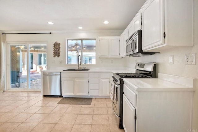 kitchen featuring light tile patterned floors, white cabinets, stainless steel appliances, and a sink