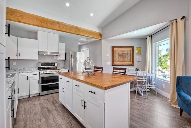 kitchen with a center island, under cabinet range hood, butcher block counters, wood finished floors, and stainless steel appliances