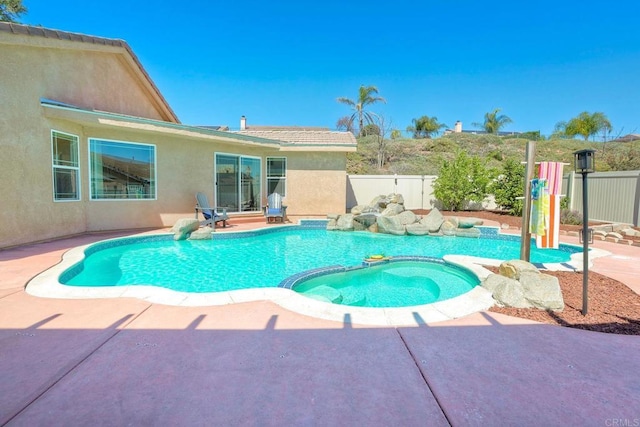 view of swimming pool with a patio, fence, and a pool with connected hot tub