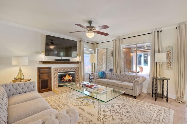 tiled living area with baseboards, ceiling fan, crown molding, and a tile fireplace