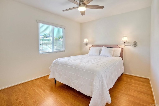 bedroom featuring baseboards, wood finished floors, and a ceiling fan