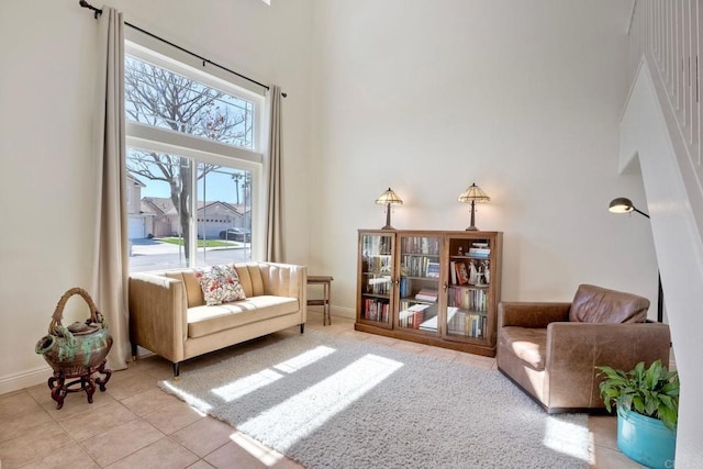 sitting room with a high ceiling, light tile patterned floors, and baseboards