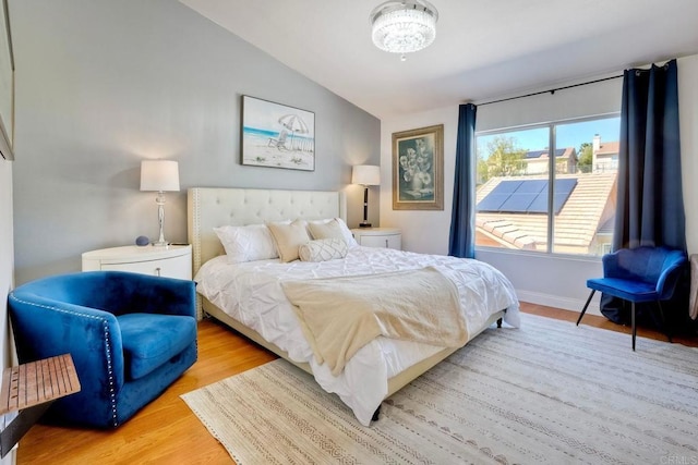 bedroom featuring baseboards, lofted ceiling, and light wood-style floors