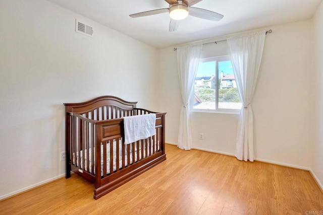 bedroom featuring ceiling fan, visible vents, baseboards, and light wood-style flooring