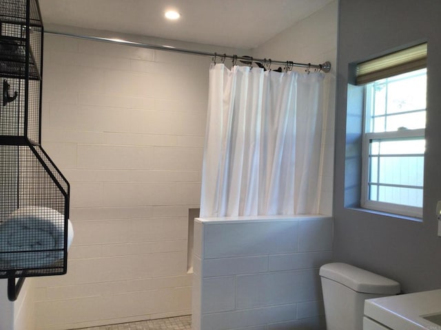 bathroom with toilet, plenty of natural light, recessed lighting, and a tile shower