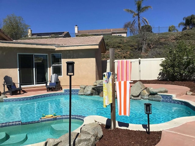 view of pool featuring a pool with connected hot tub and fence