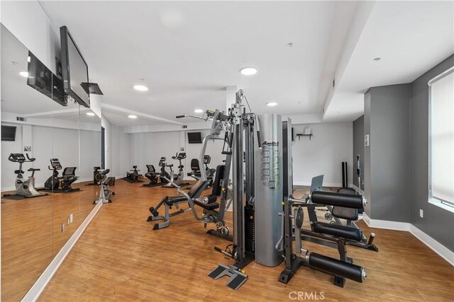 workout area featuring recessed lighting, light wood-type flooring, and baseboards