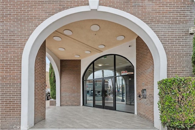 view of exterior entry with brick siding and french doors