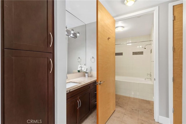 bathroom featuring tile patterned floors, tiled shower / bath, and vanity