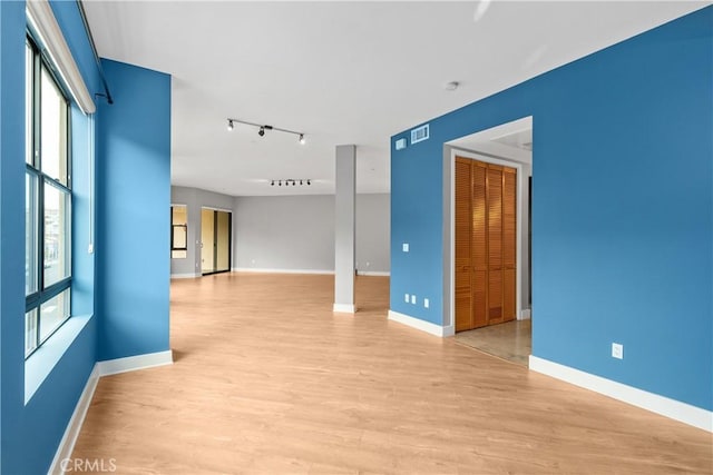 spare room with visible vents, rail lighting, baseboards, and light wood-style floors