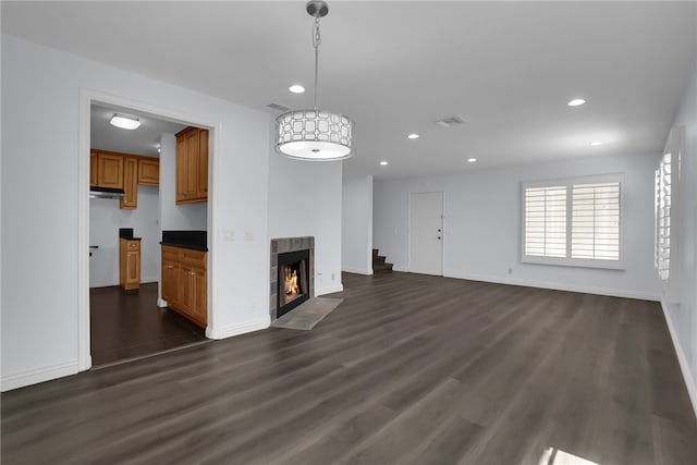 unfurnished living room featuring recessed lighting, baseboards, dark wood finished floors, and a tiled fireplace